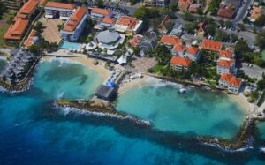 A luxury oceanfront resort in Curaçao with turquoise waters, palm trees, and elegant infinity pools overlooking the Caribbean Sea