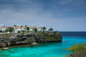 Lagun Beach Curaçao with turquoise water, fishing boats, and cliffs surrounding the small sandy bay.