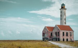 Klein Curaçao with white sandy beach, turquoise water, pink lighthouse, and shipwrecks along the shore.