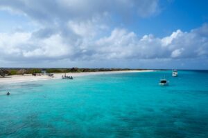 Klein Curaçao with white sandy beach, turquoise water, pink lighthouse, and shipwrecks along the shore. 