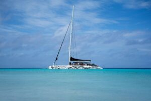 Klein Curaçao with white sandy beach, turquoise water, pink lighthouse, and shipwrecks along the shore.