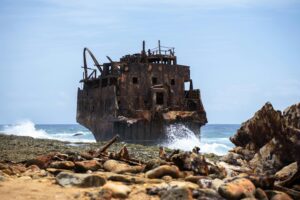 Klein Curaçao with white sandy beach, turquoise water, pink lighthouse, and shipwrecks along the shore.