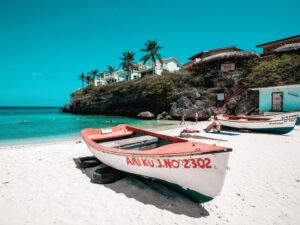Traveler using a smartphone with eSIM in Curaçao, staying connected on the beach with turquoise water in the background.