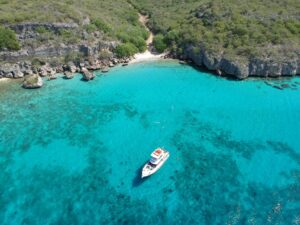 Kleine Knip Curaçao, a small sandy bay with turquoise waters surrounded by green hills and cliffs.