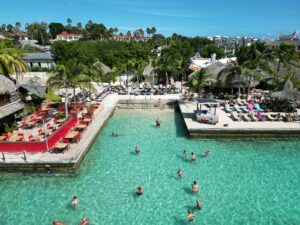 Beautiful view of Jan Thiel Beach with turquoise water and tropical palm trees, showing beachfront resorts and vacation rentals