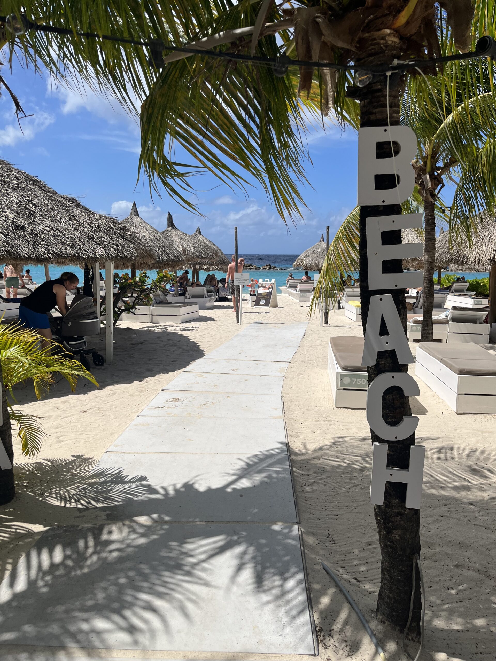 Tropical view of Mambo Beach in Curaçao with soft white sand, turquoise waters, and nearby beachfront hotels and apartments