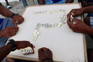 Locals playing domino at a Curaçao snek with laughter and drinks on the table